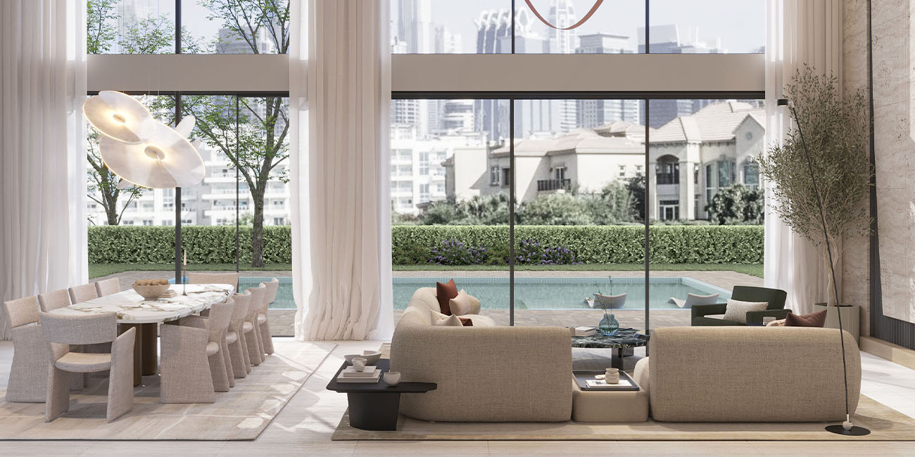 Modern living room with large windows, beige furniture, and view of pool and garden. Elementa Interior Design Dubai