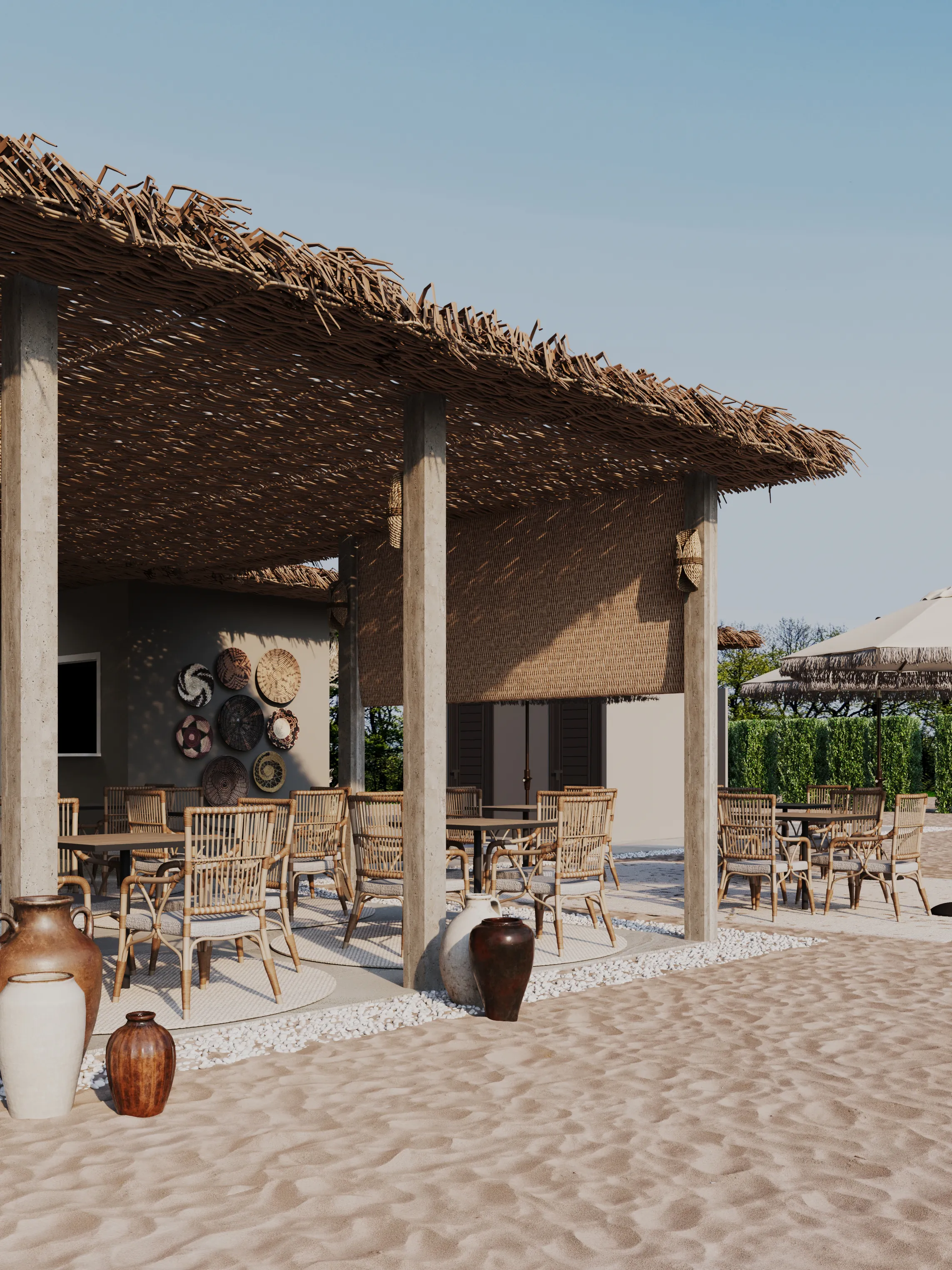 Outdoor beach lounge with wicker chairs, thatched roof, and decorative pottery on sandy ground.